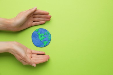 Photo of Woman and model of planet on green background, flat lay with space for text. Earth Day