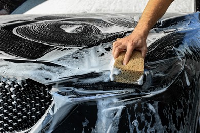 Photo of Worker washing auto with sponge, closeup view