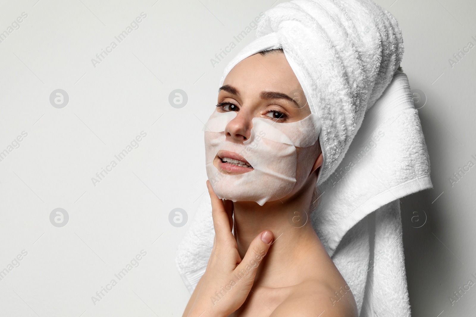 Photo of Beautiful woman with cotton face and eye masks against light background. Space for text