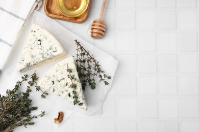 Tasty blue cheese with thyme and honey on white tiled table, flat lay. Space for text