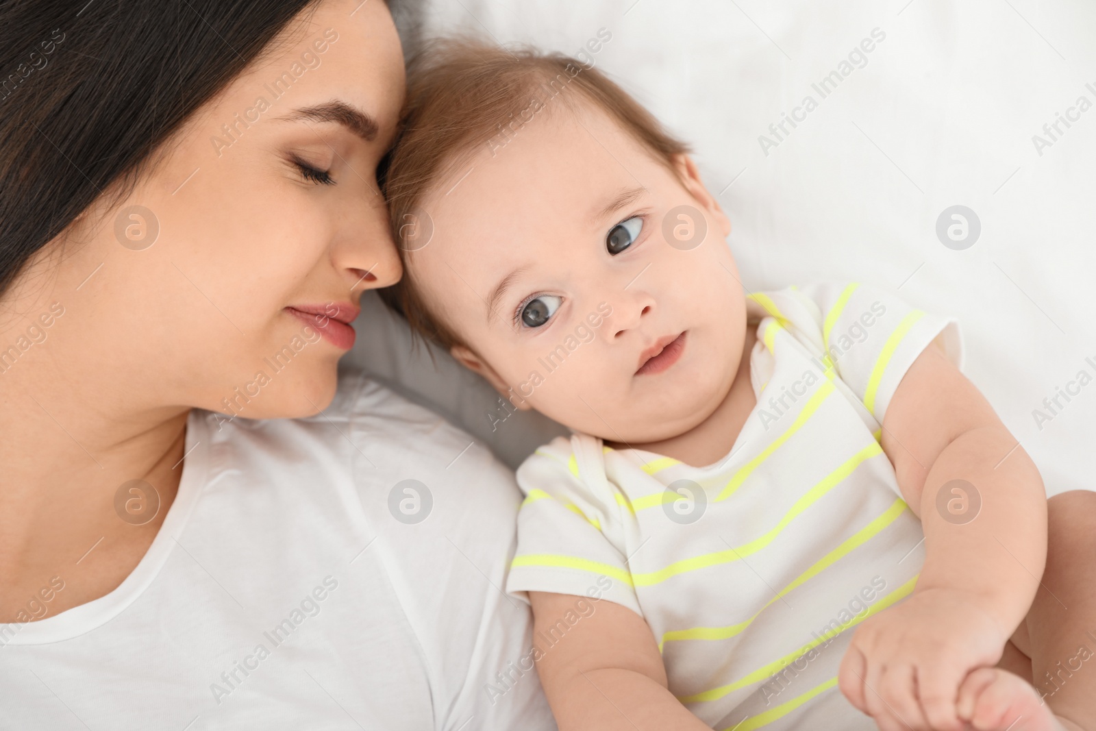 Photo of Portrait of mother with her cute baby lying on bed, top view