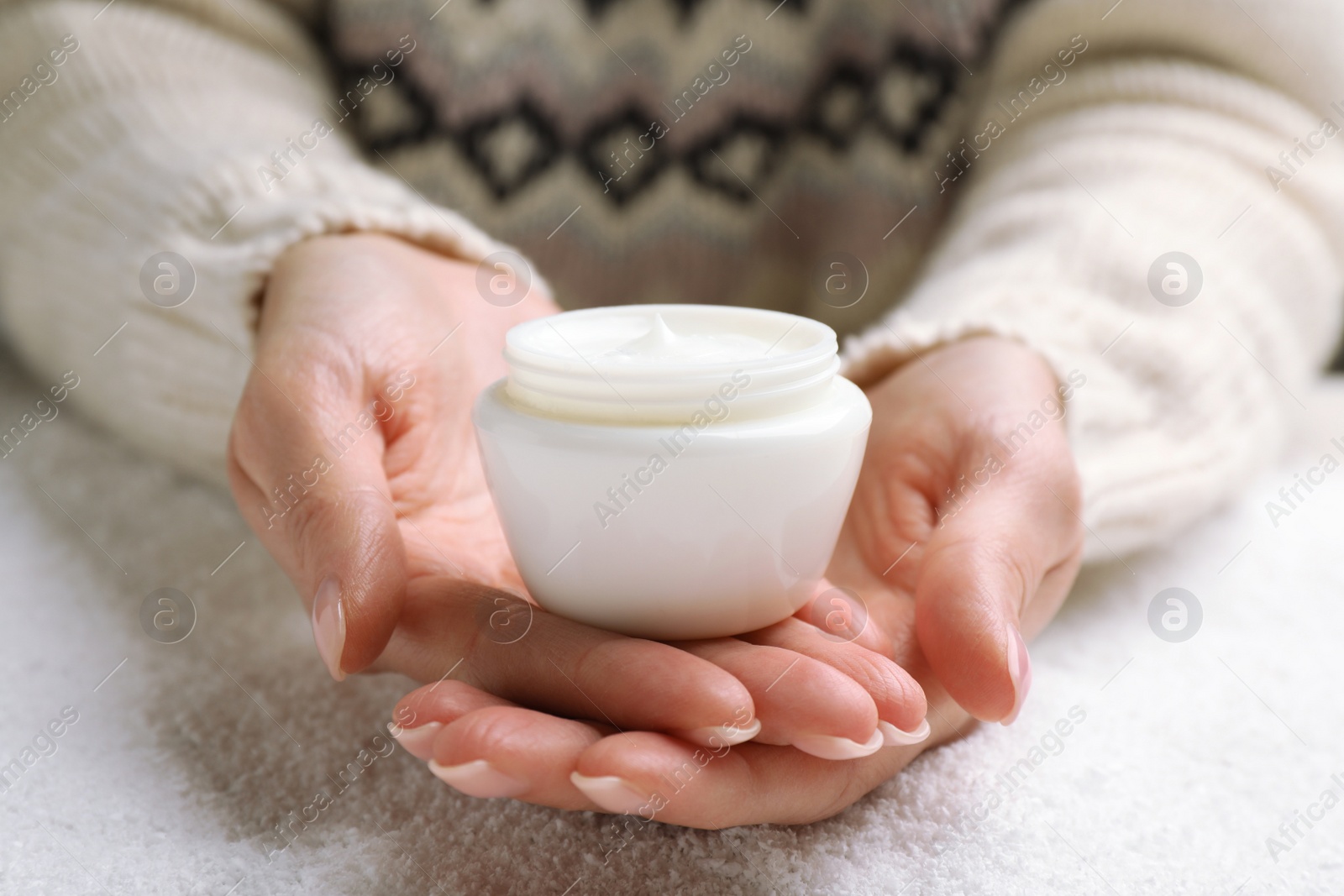 Photo of Woman with jar of hand cream over snow, closeup