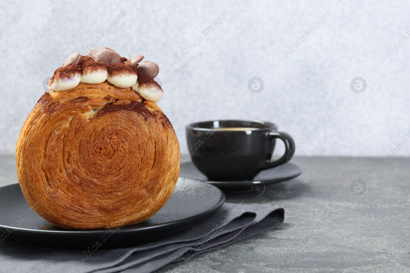 Photo of Round croissant with chocolate chips and cream served on grey table, space for text. Tasty puff pastry