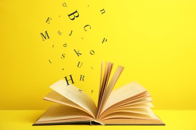Image of Open book with letters flying out of it on yellow background