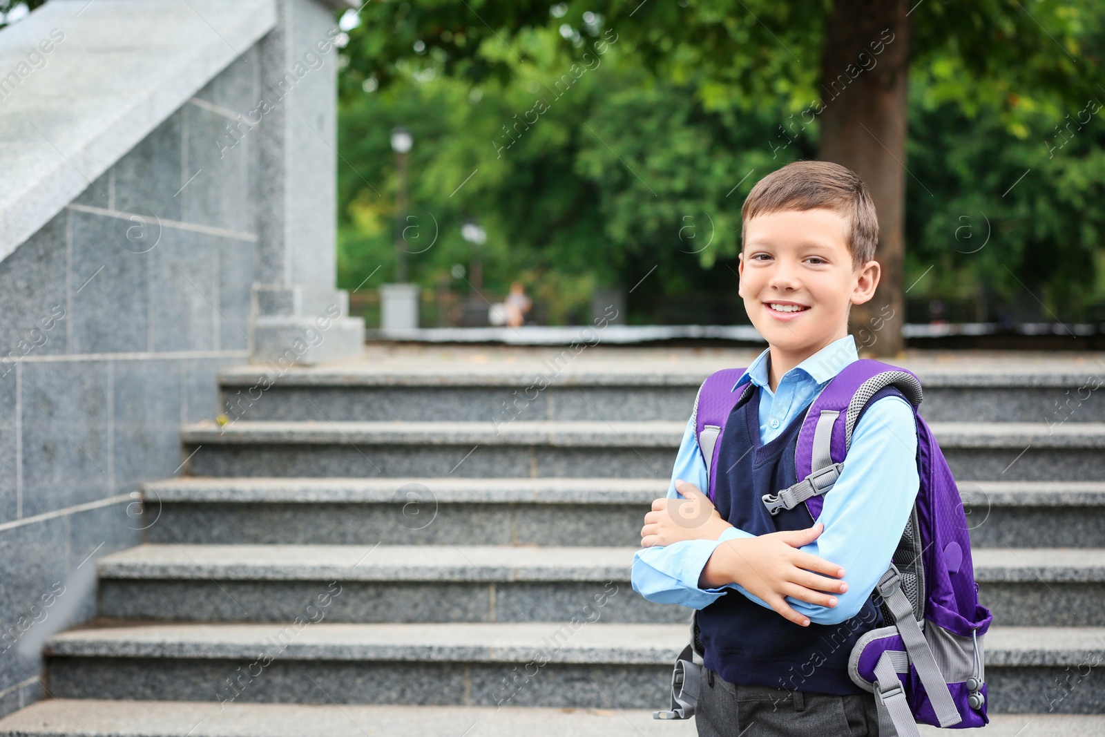 Photo of Cute school child with backpack near stairs in park