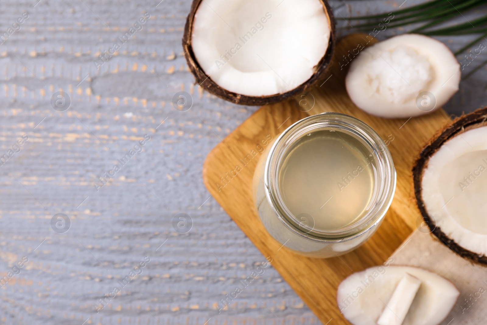 Photo of Coconut oil on grey wooden table, flat lay. Space for text