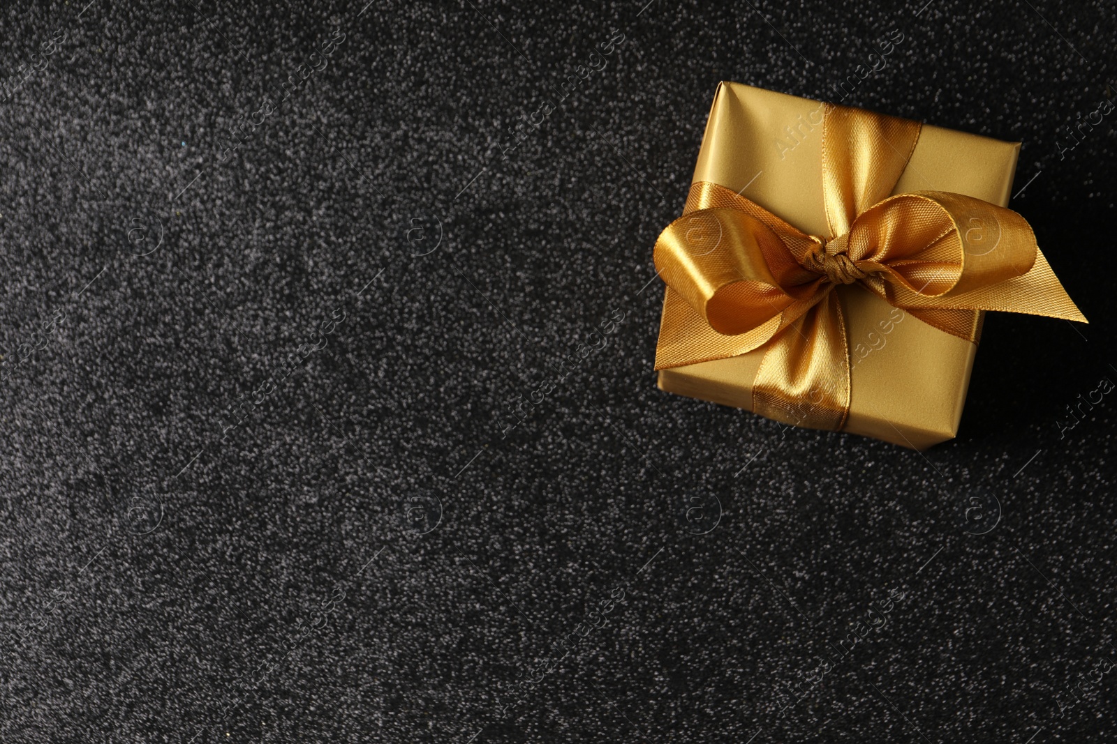 Photo of Beautifully wrapped gift box on black background, top view. Space for text