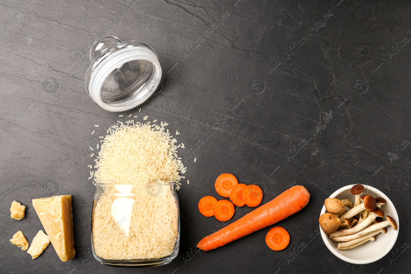 Photo of Flat lay composition with different ingredients on black table, space for text. Risotto recipe