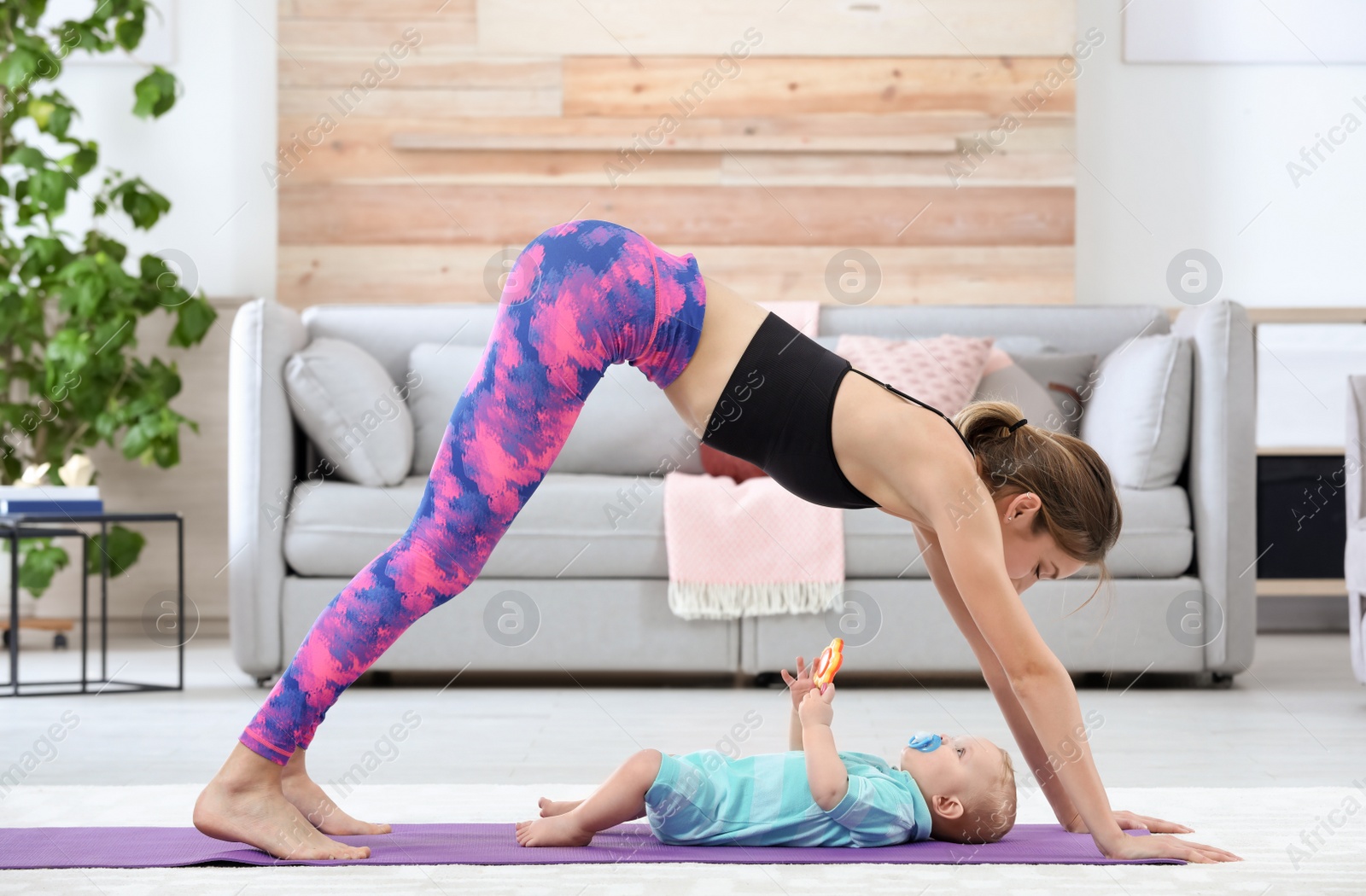 Photo of Young sportive woman doing exercise with her son at home. Fitness training