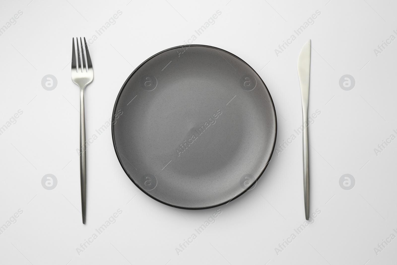 Photo of Empty plate, fork and knife on white background, top view