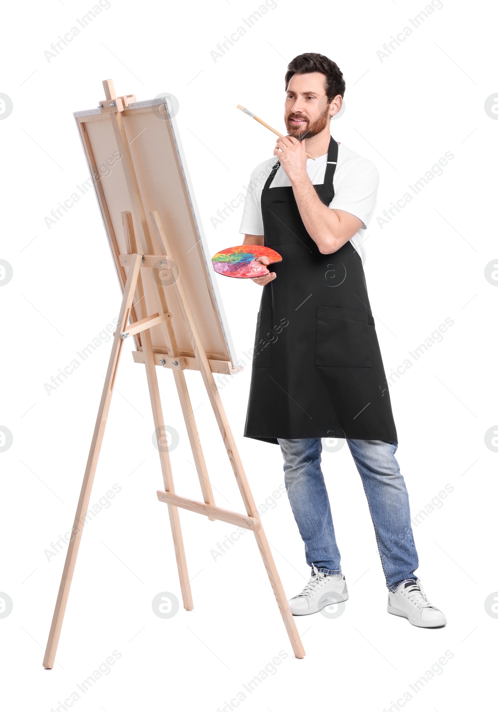 Photo of Artist with brush painting against white background. Using easel to hold canvas