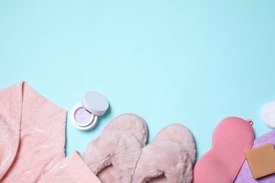 Flat lay composition with bathrobe, slippers and accessories on light blue background. Space for text