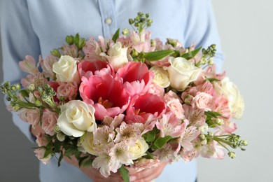 Woman with beautiful bouquet of fresh flowers on light background, closeup