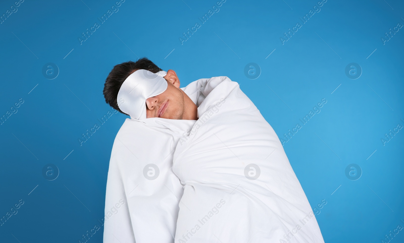 Photo of Man in mask with blanket sleeping on blue background