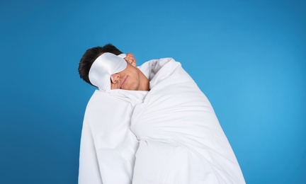 Photo of Man in mask with blanket sleeping on blue background