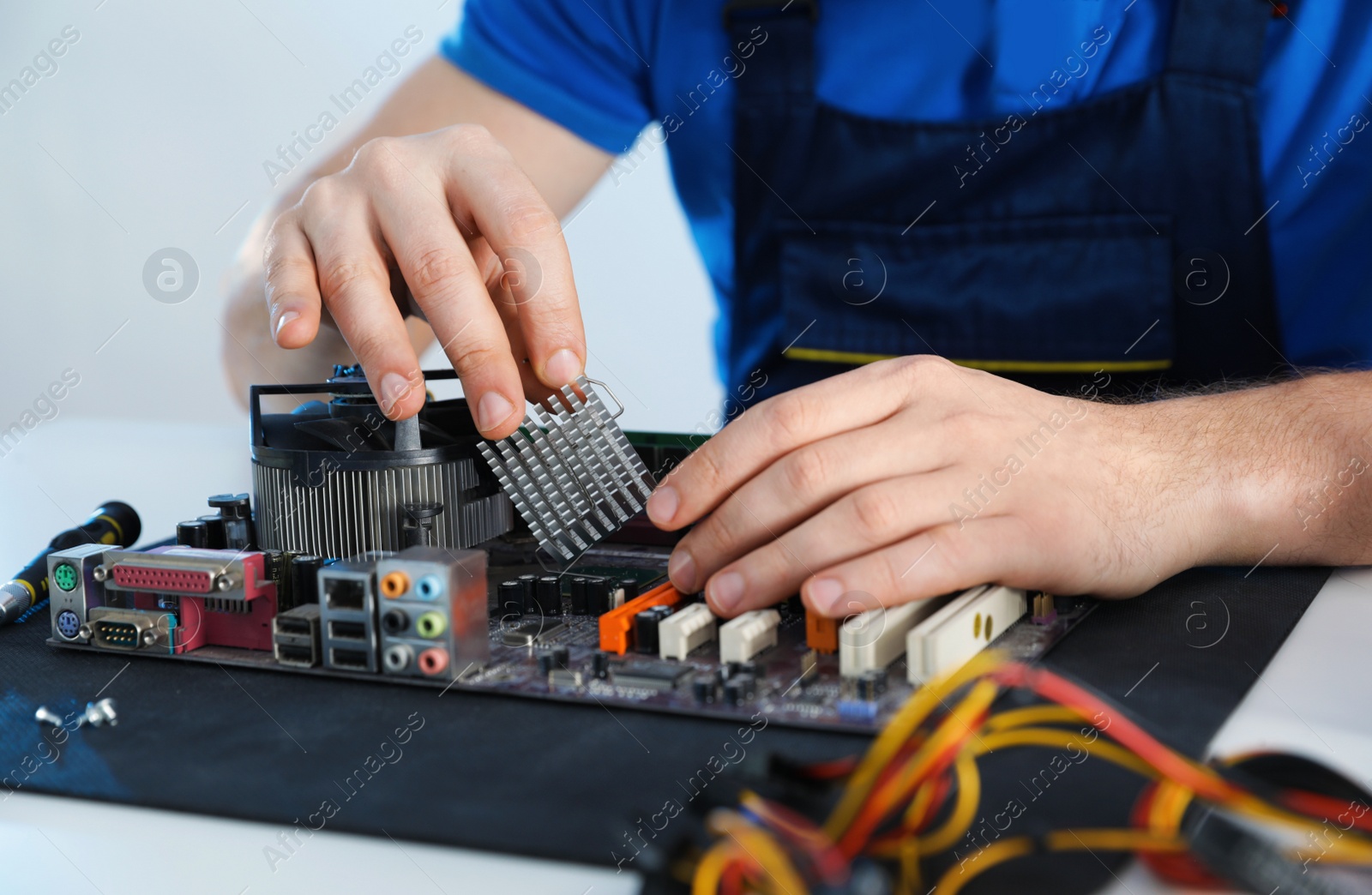 Photo of Male technician repairing motherboard at table, closeup