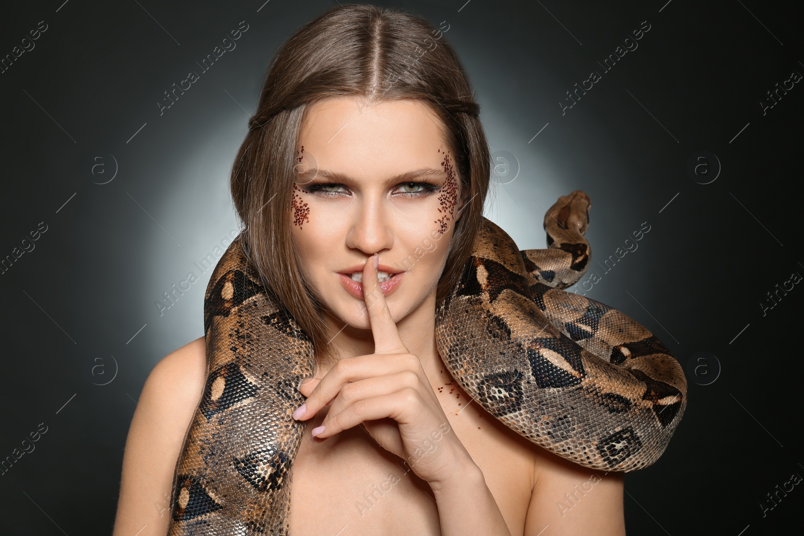 Photo of Beautiful woman with boa constrictor on dark background