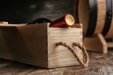 Photo of Crate with bottle of wine on wooden table