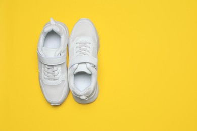 Pair of comfortable sports shoes on yellow background, flat lay. Space for text