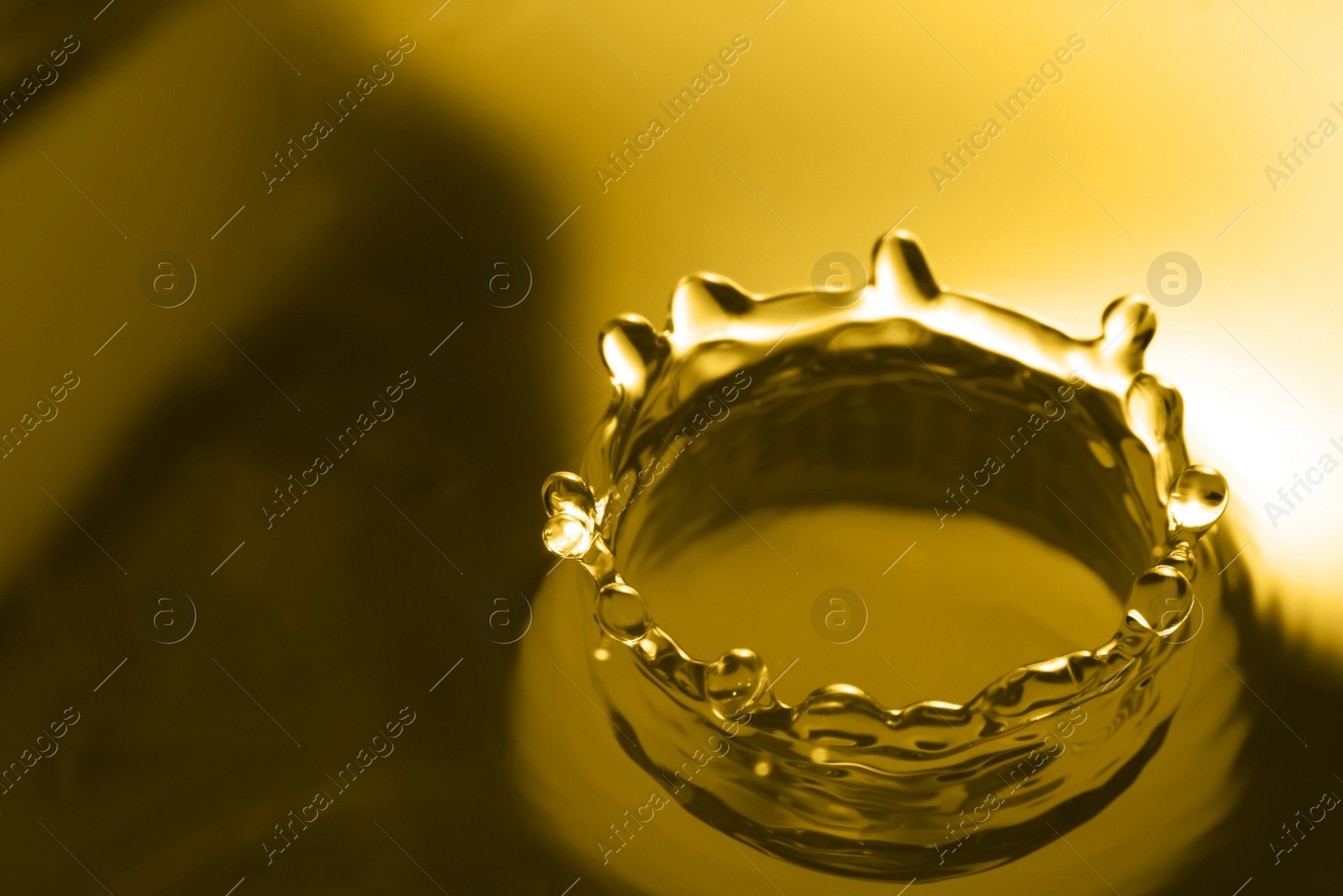 Image of Splash of golden oily liquid as background, closeup. Space for text