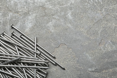 Photo of Pile of metal nails on grey stone background, flat lay. Space for text