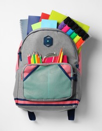 Photo of Backpack with different school stationery on white background, top view