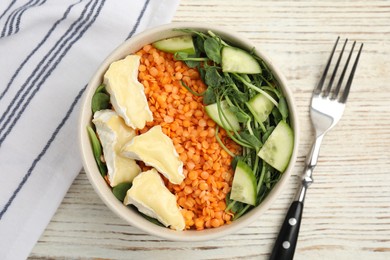 Delicious lentil bowl with soft cheese and cucumber on white wooden table, flat lay