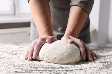 Man kneading dough at table in kitchen, closeup