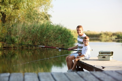 Photo of Dad and son fishing together on sunny day