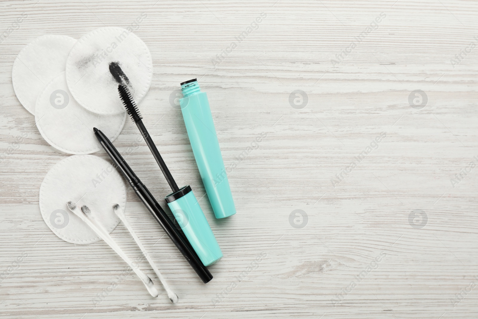 Photo of Dirty cotton pads, swabs and cosmetic products on white wooden background, flat lay. Space for text