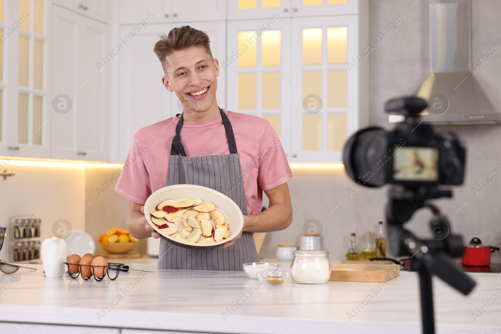 Photo of Smiling food blogger explaining something while recording video in kitchen