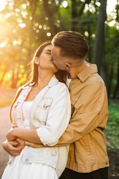 Affectionate happy young couple kissing in park