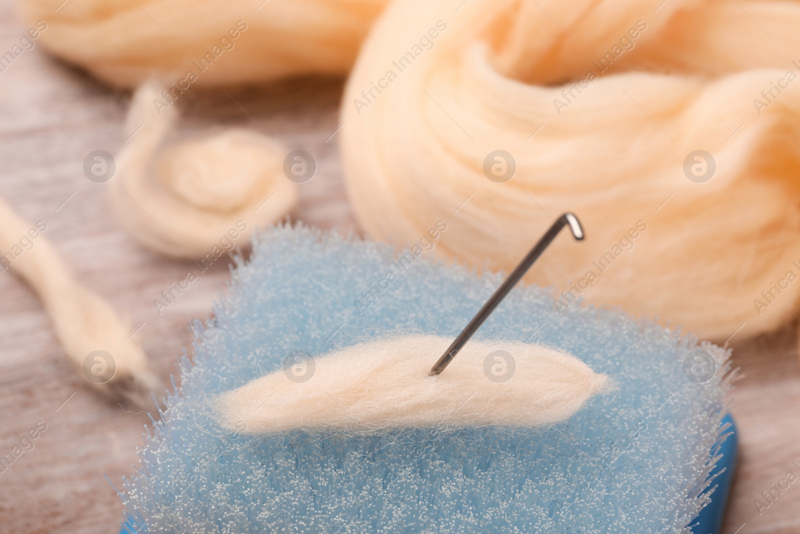 Photo of Felting wool, brush and needle on table, closeup