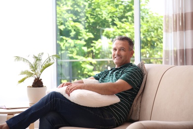 Photo of Man relaxing on sofa with comfortable pillows at home