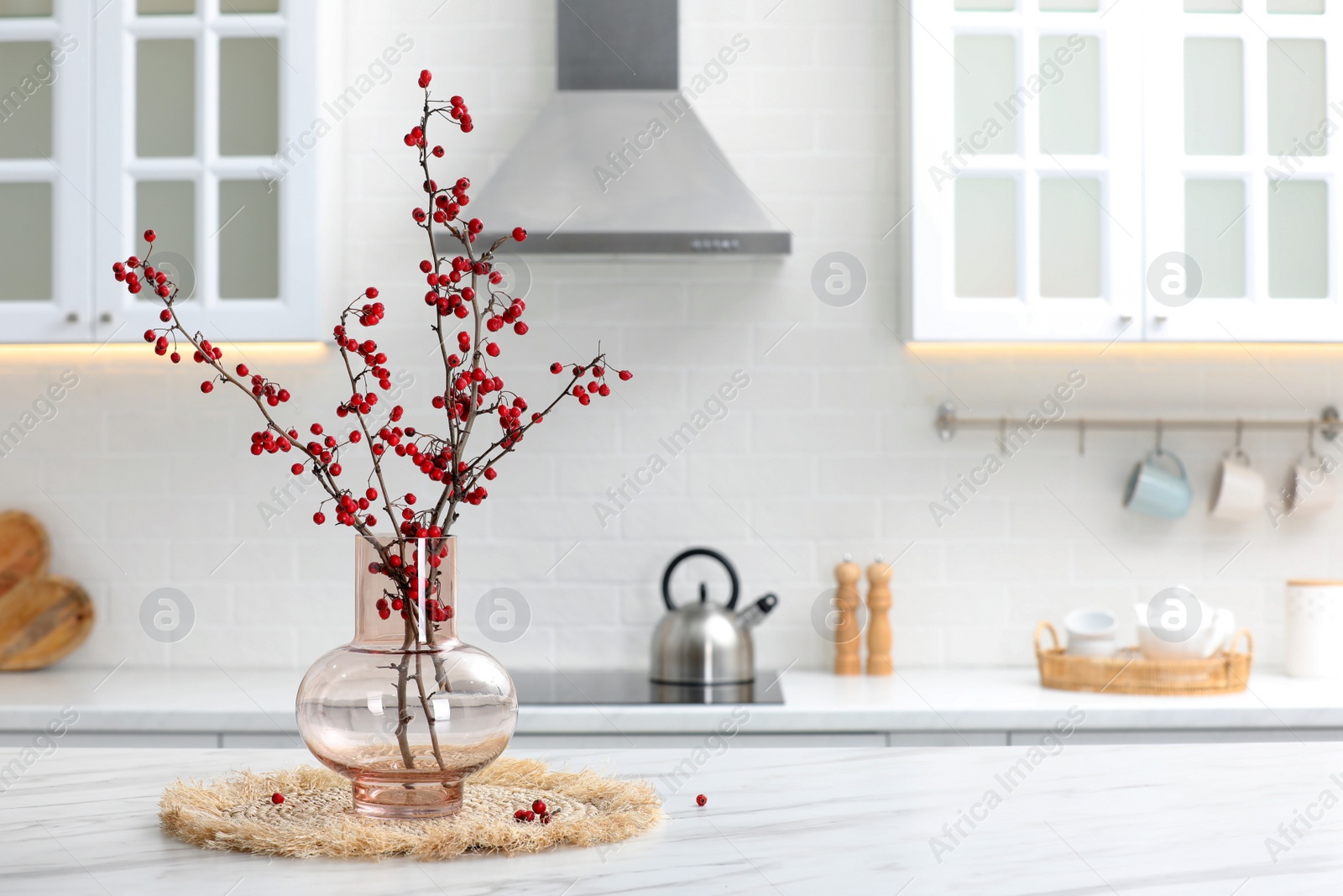 Photo of Hawthorn branches with red berries on table in kitchen, space for text