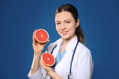 Photo of Nutritionist with ripe grapefruit on blue background