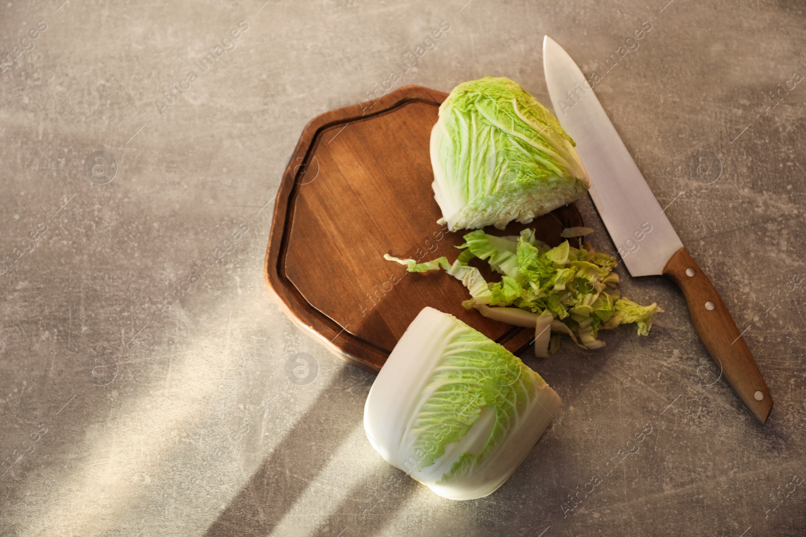 Photo of Cut fresh Chinese cabbage and knife on light grey table