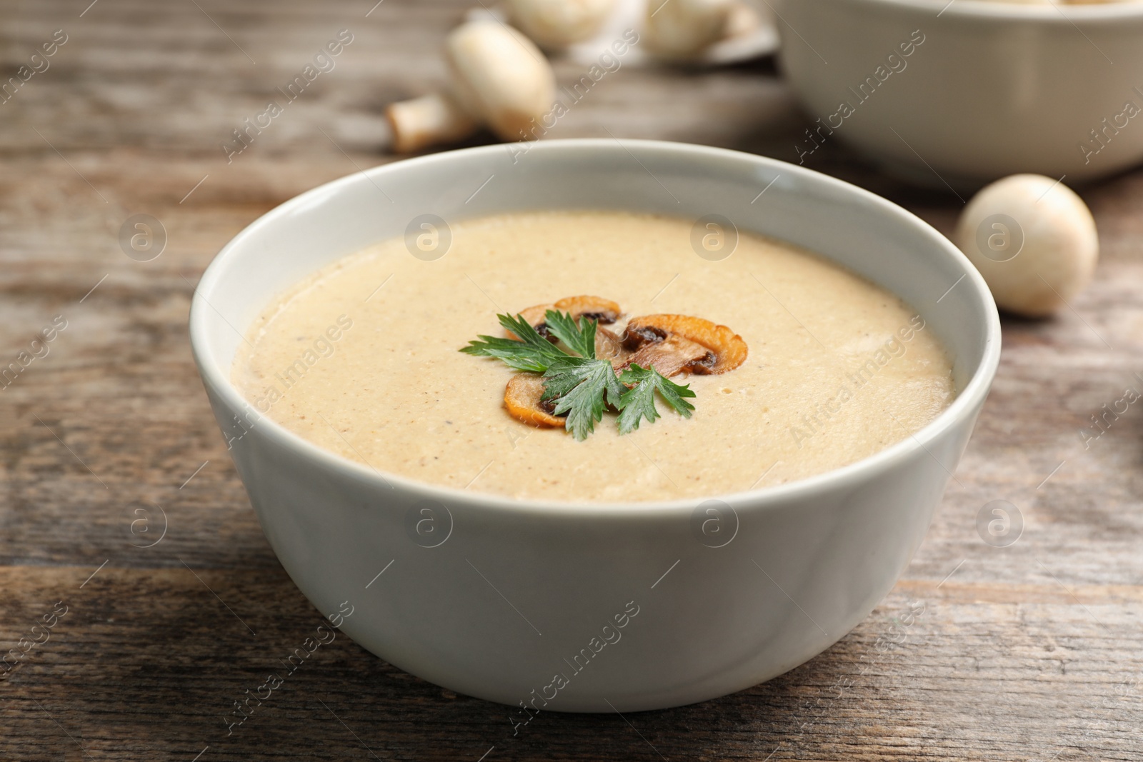 Photo of Bowl of fresh homemade mushroom soup on wooden table