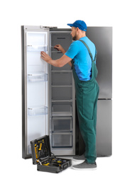 Photo of Male technician repairing refrigerator on white background
