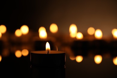 Burning candle on surface in darkness, closeup. Space for text