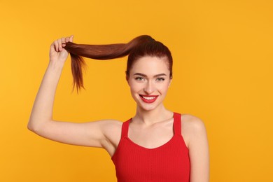 Photo of Happy woman with red dyed hair on orange background
