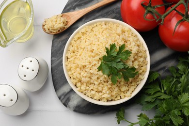 Delicious bulgur with parsley in bowl served on table, flat lay