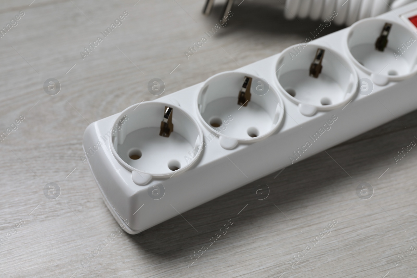 Photo of Power strip on wooden floor, closeup. Electrician's equipment