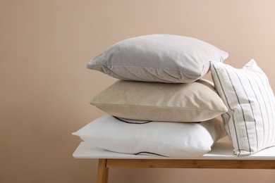 Photo of Soft pillows on table near beige wall. Space for text