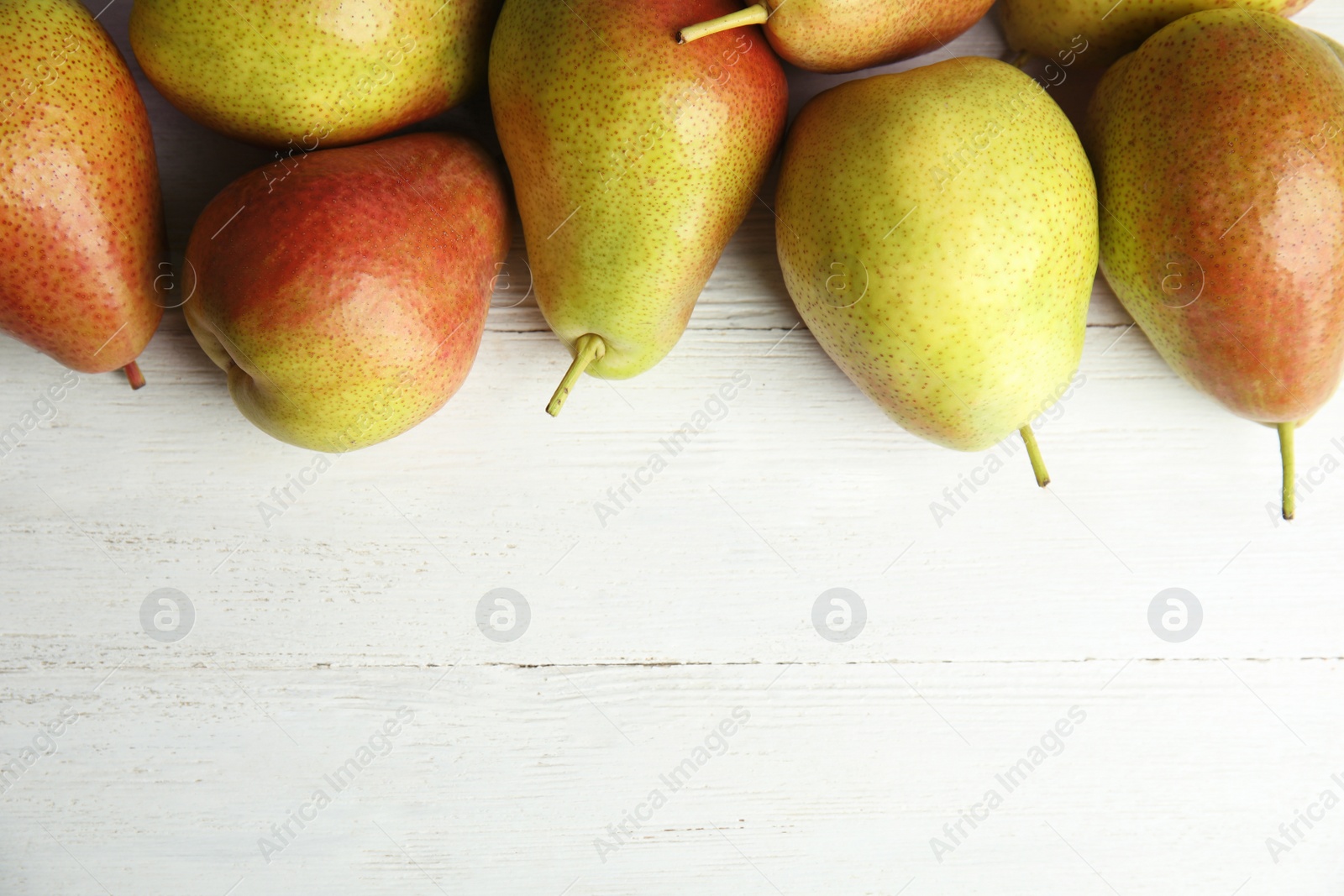 Photo of Ripe juicy pears on white wooden table, flat lay. Space for text