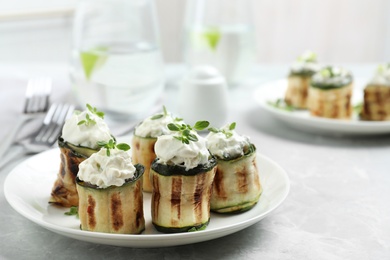 Photo of Stuffed zucchini rolls on grey marble table. Space for text