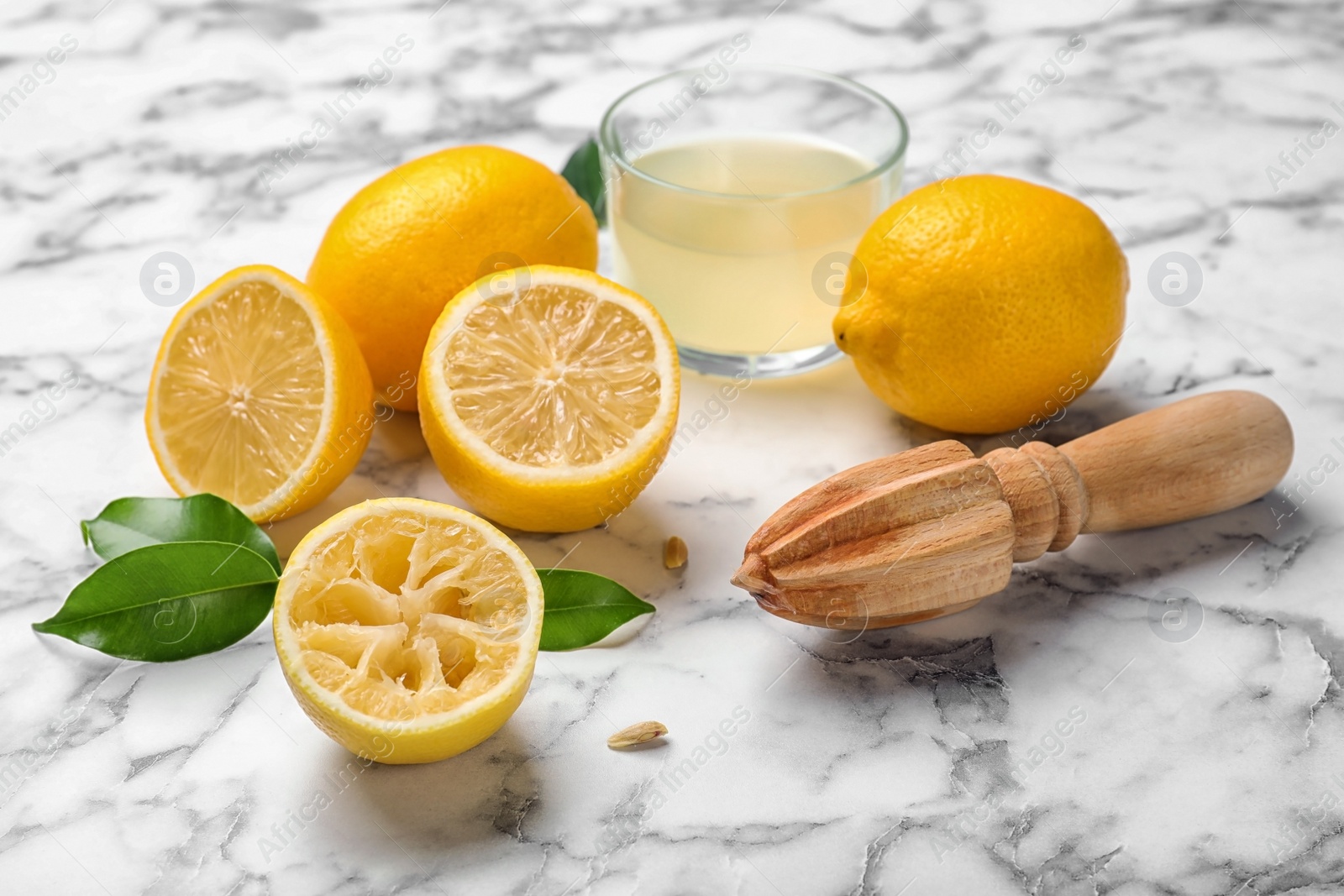 Photo of Composition with freshly squeezed juice, lemons and wooden reamer on marble table
