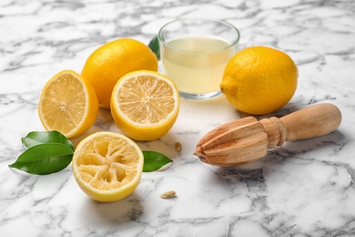 Composition with freshly squeezed juice, lemons and wooden reamer on marble table