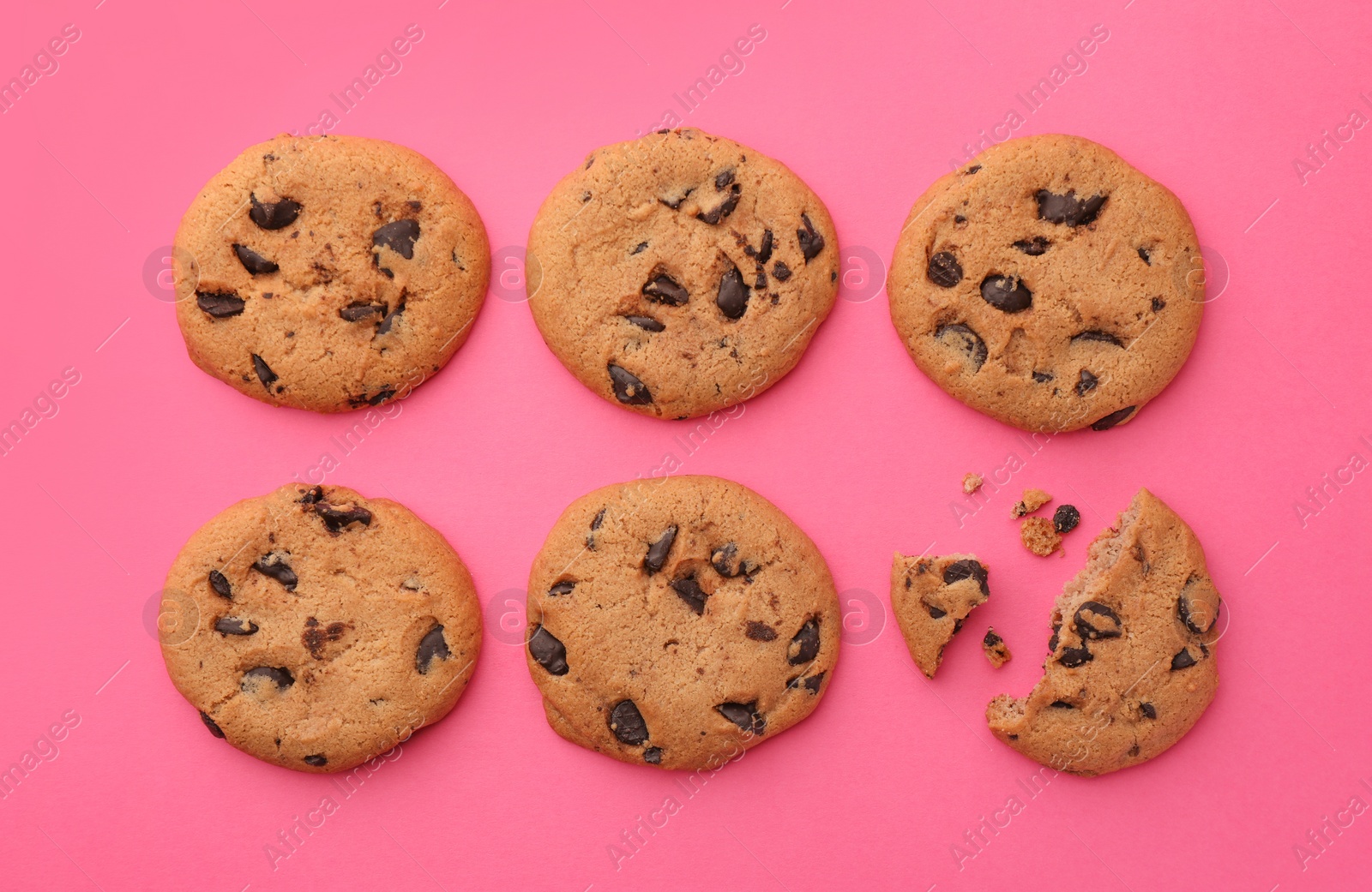 Photo of Many delicious chocolate chip cookies on pink background, flat lay