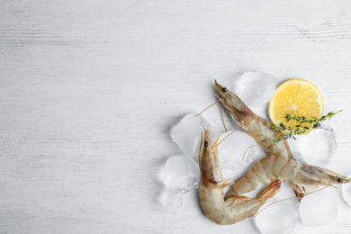 Photo of Flat lay composition with raw shrimps on white wooden table. Space for text